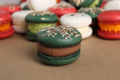 Beautifully decorated Christmas macarons on brown background, closeup