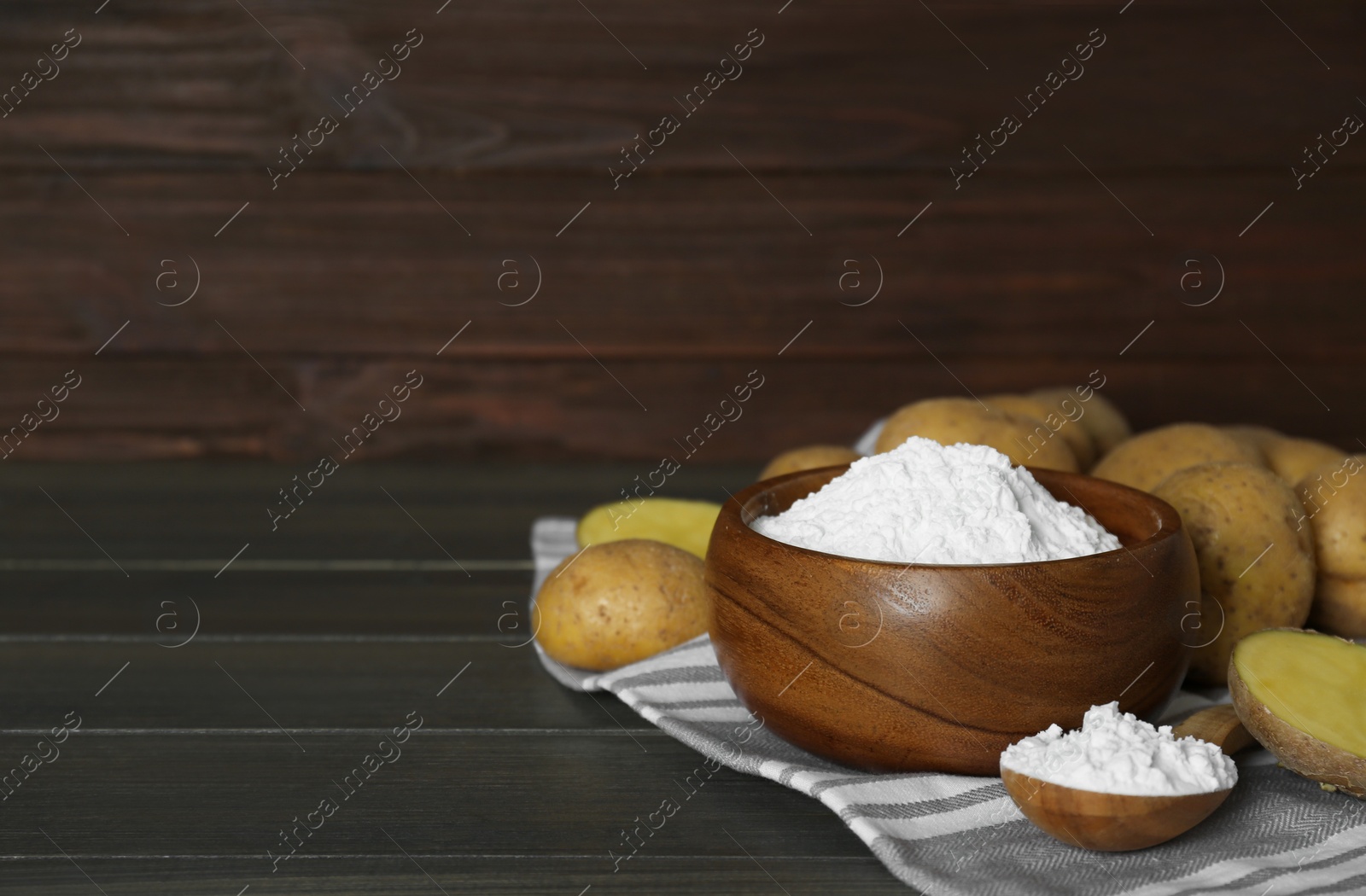 Photo of Starch and fresh raw potatoes on wooden table. Space for text