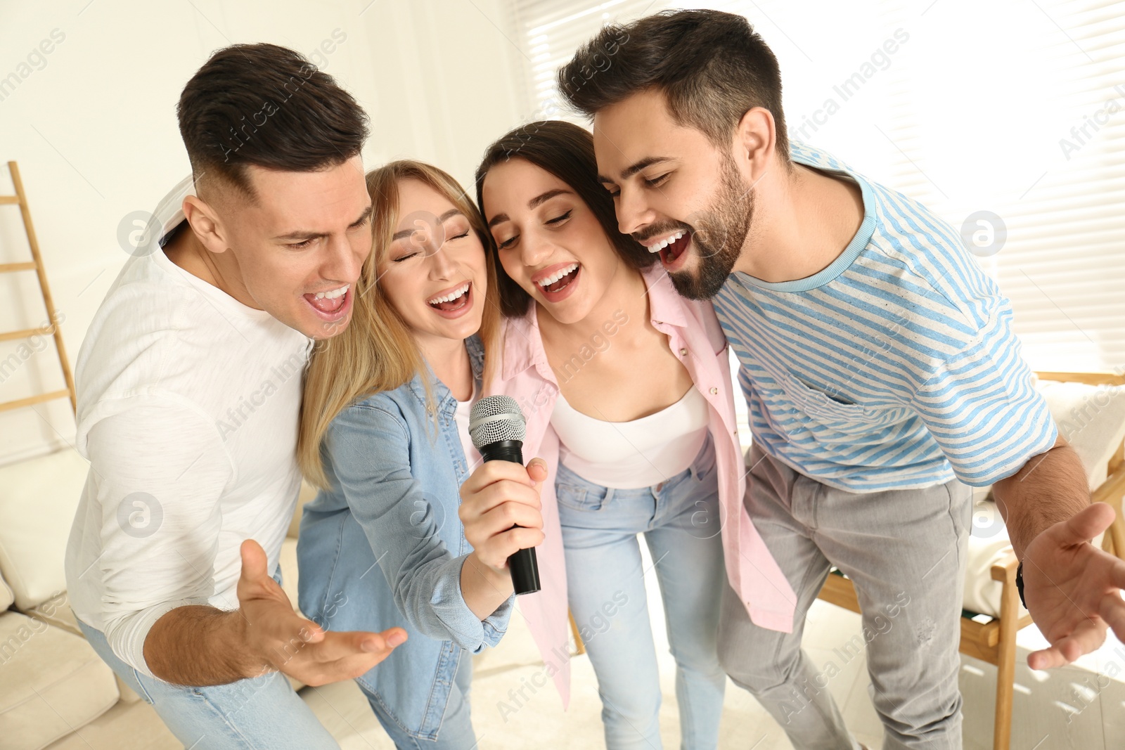 Photo of Happy friends singing karaoke together at home