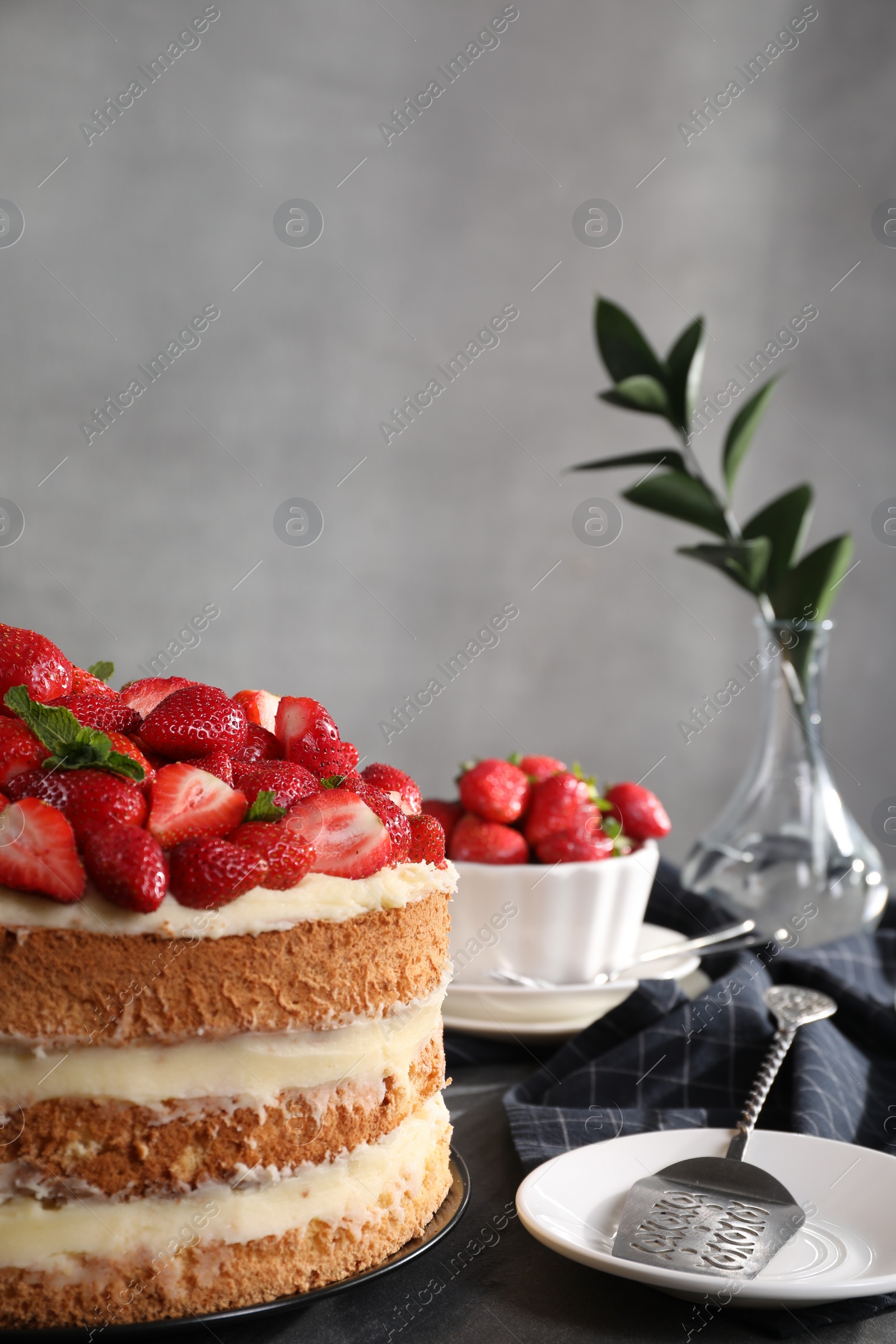Photo of Tasty cake with fresh strawberries and mint on table against gray background, space copy text