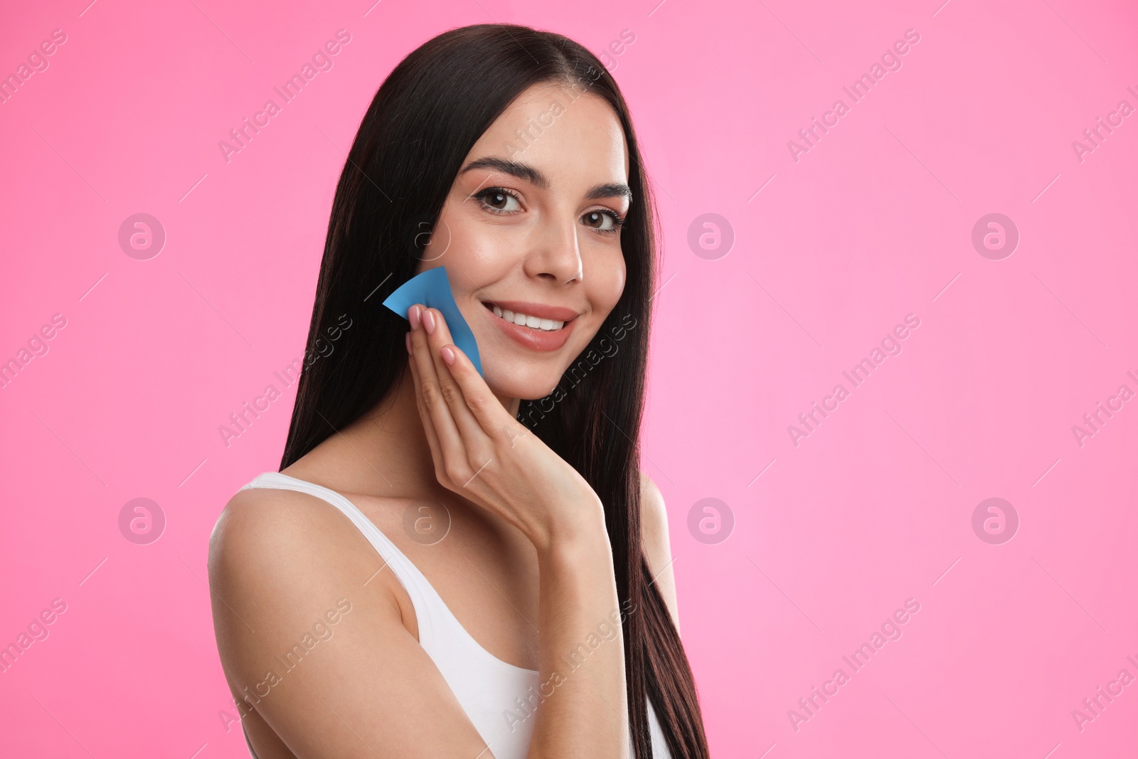 Photo of Beautiful woman using mattifying wipe on pink background, space for text