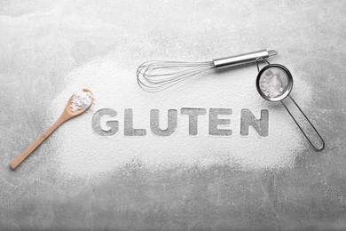 Photo of Word Gluten written with flour and different kitchen utensils on grey background, flat lay