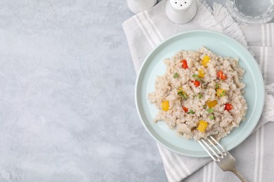 Photo of Delicious barley porridge with vegetables and microgreens on gray table, top view. Space for text