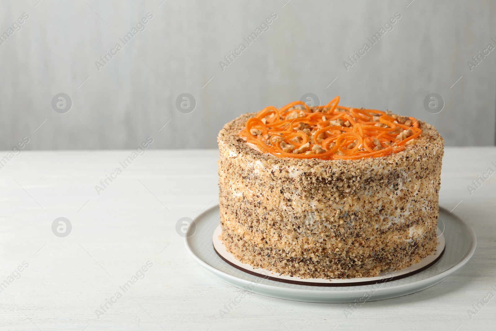 Photo of Dish with delicious carrot cake on wooden table against grey background. Space for text