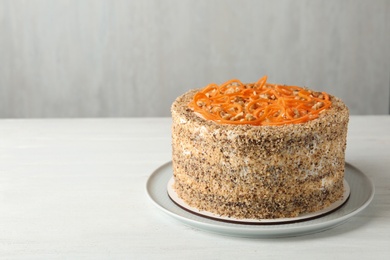 Photo of Dish with delicious carrot cake on wooden table against grey background. Space for text