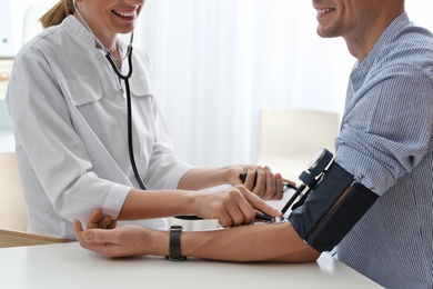 Photo of Doctor checking patient's blood pressure in hospital, closeup. Cardiology concept