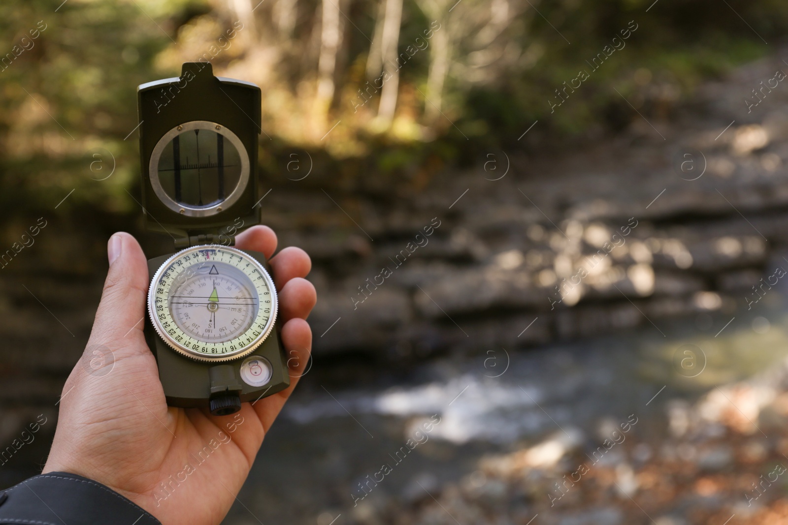 Photo of Man using compass for navigation during journey outdoors, closeup