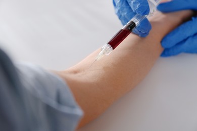 Photo of Nurse drawing blood sample from patient in clinic, closeup