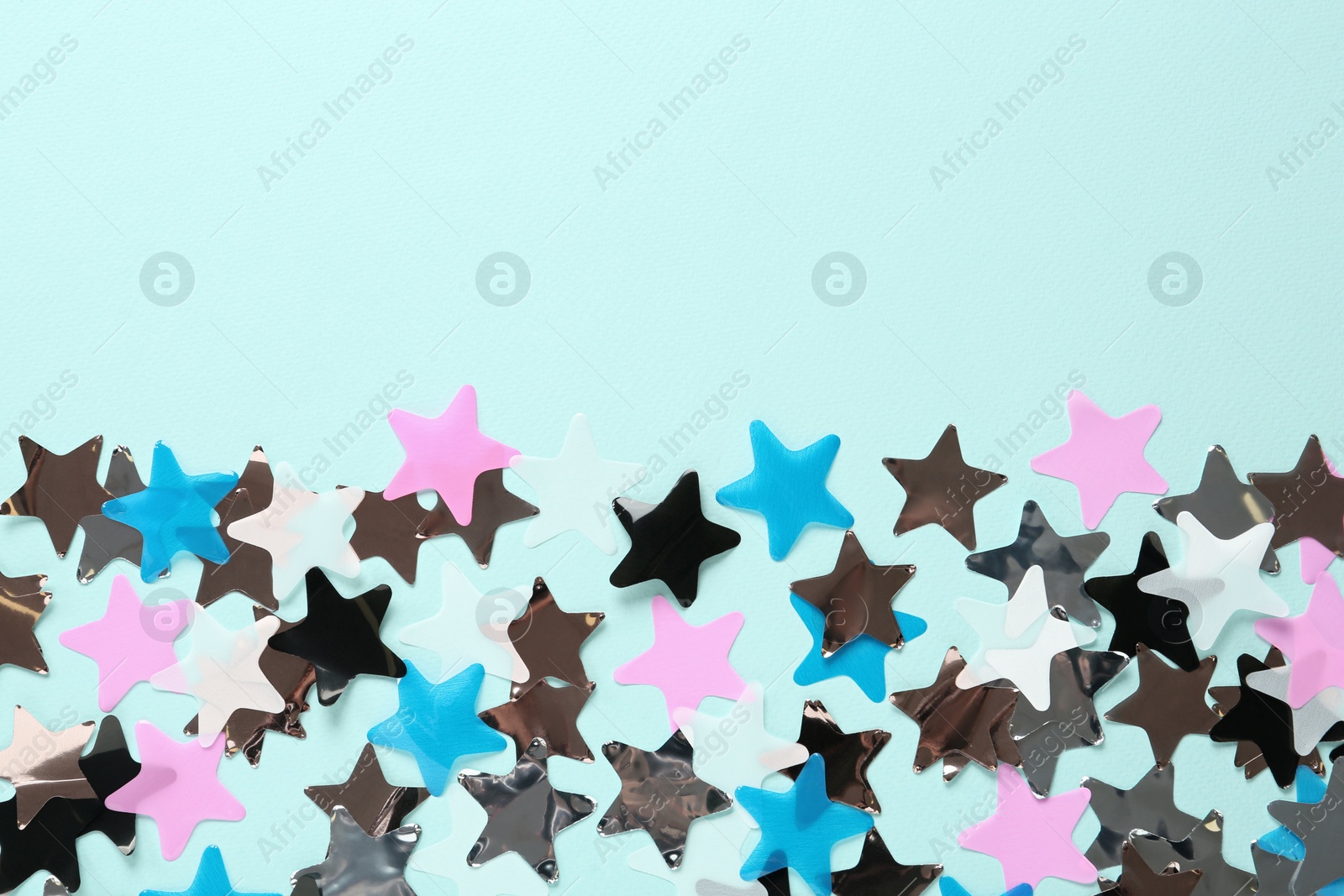 Photo of Shiny colorful confetti on light blue background, flat lay. Space for text
