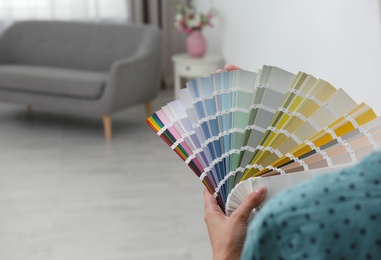 Photo of Female interior designer with color palette samples indoors, closeup. Space for text
