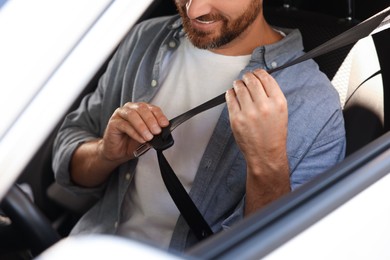 Photo of Man pulling seat belt in car, closeup