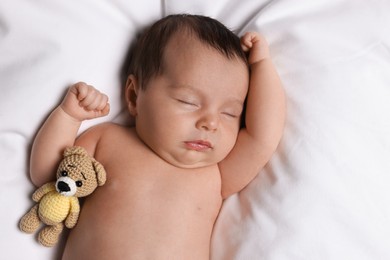 Photo of Cute little baby with toy bear sleeping on soft bed, top view
