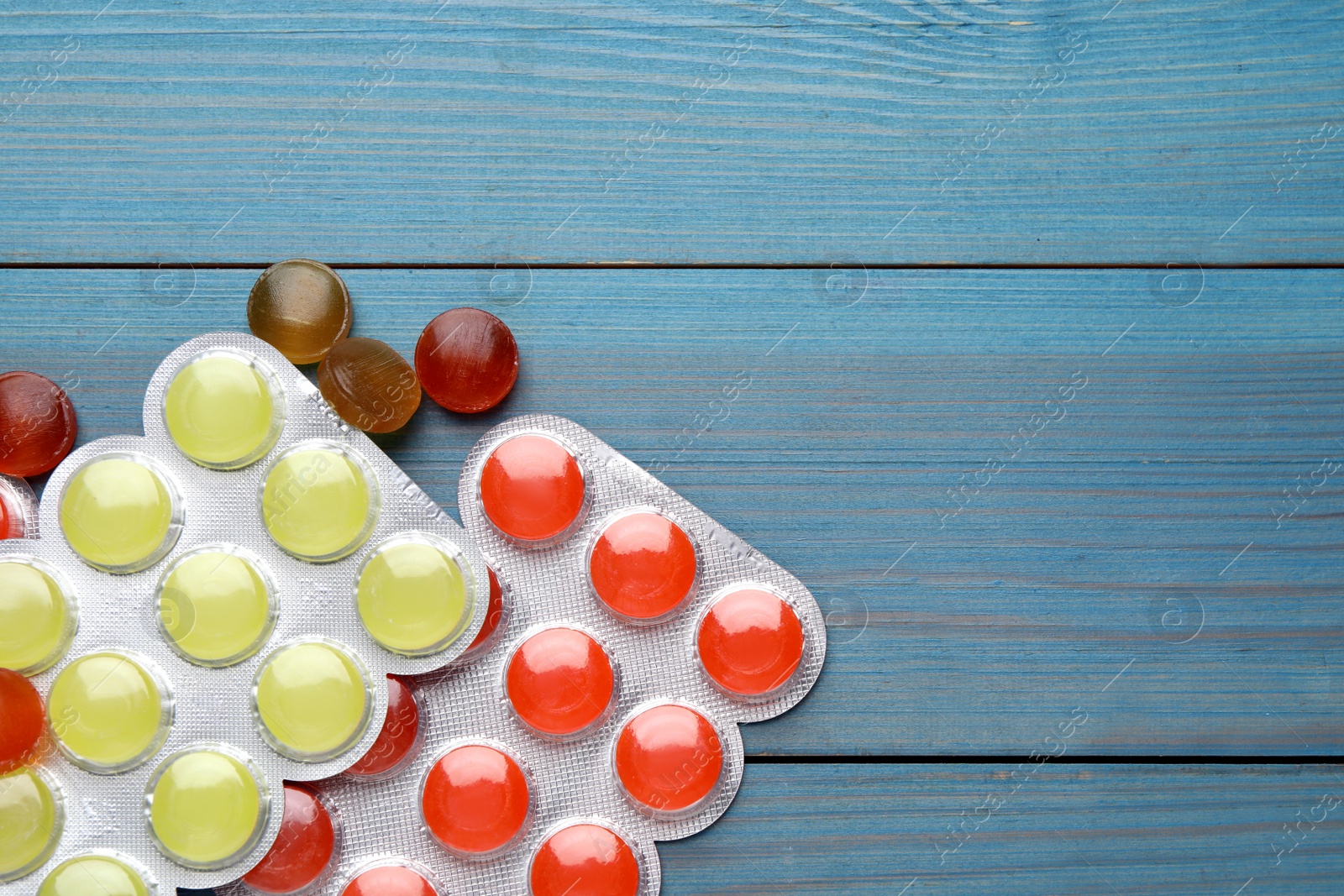 Photo of Colorful cough drops on blue wooden background, flat lay. Space for text