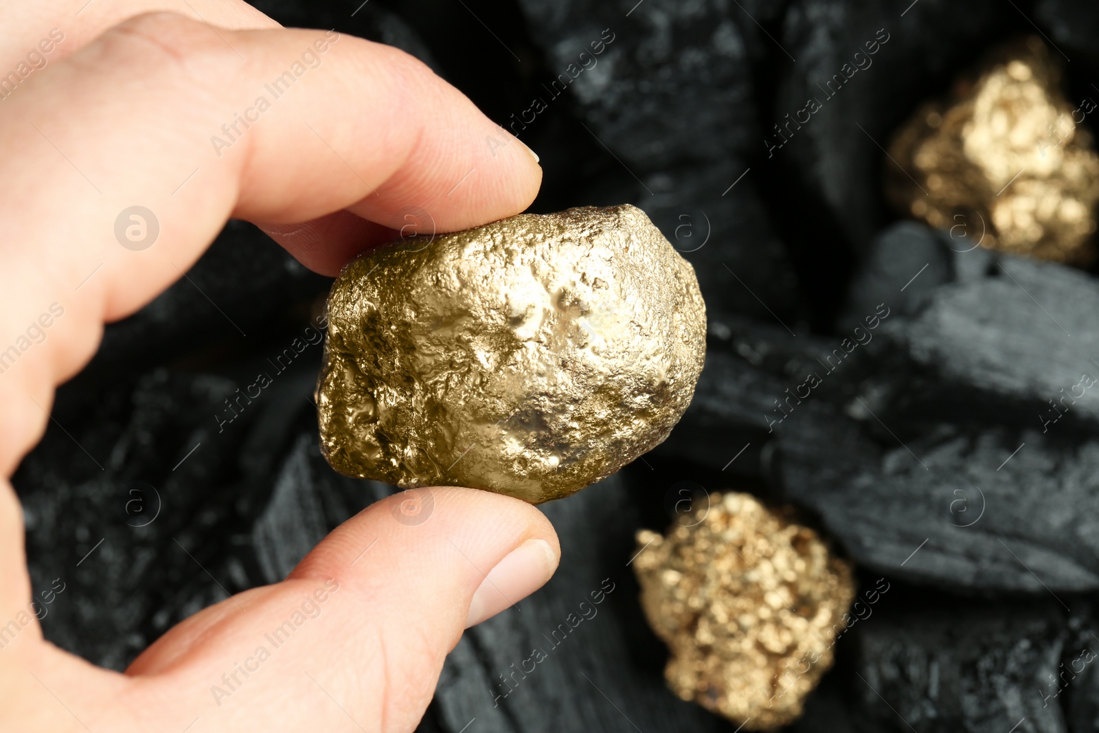 Photo of Woman holding gold nugget on blurred background, closeup. Space for text