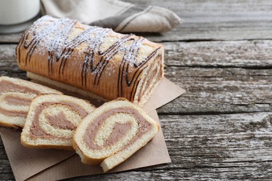 Photo of Tasty cake roll with cream on wooden table, space for text