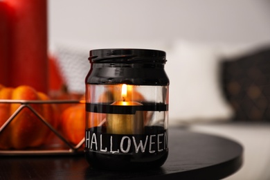 Photo of Burning candle on table in room. Idea for Halloween interior