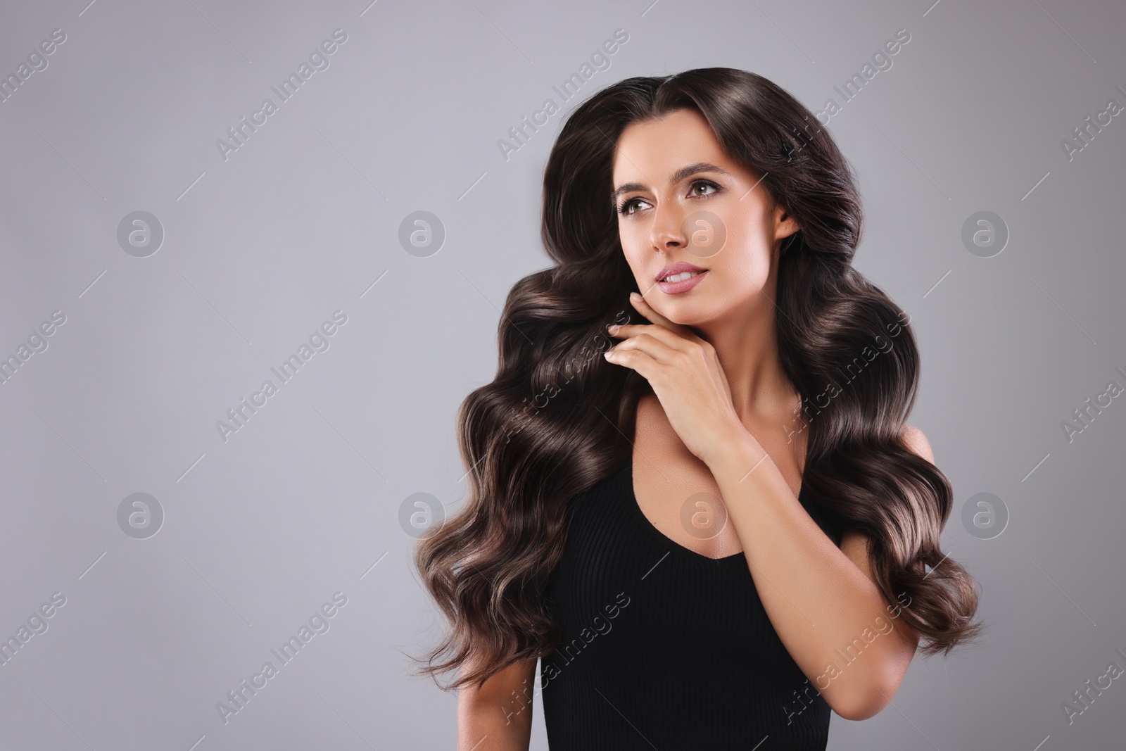 Image of Gorgeous woman with shiny wavy hair on grey background, space for text. Professional hairstyling