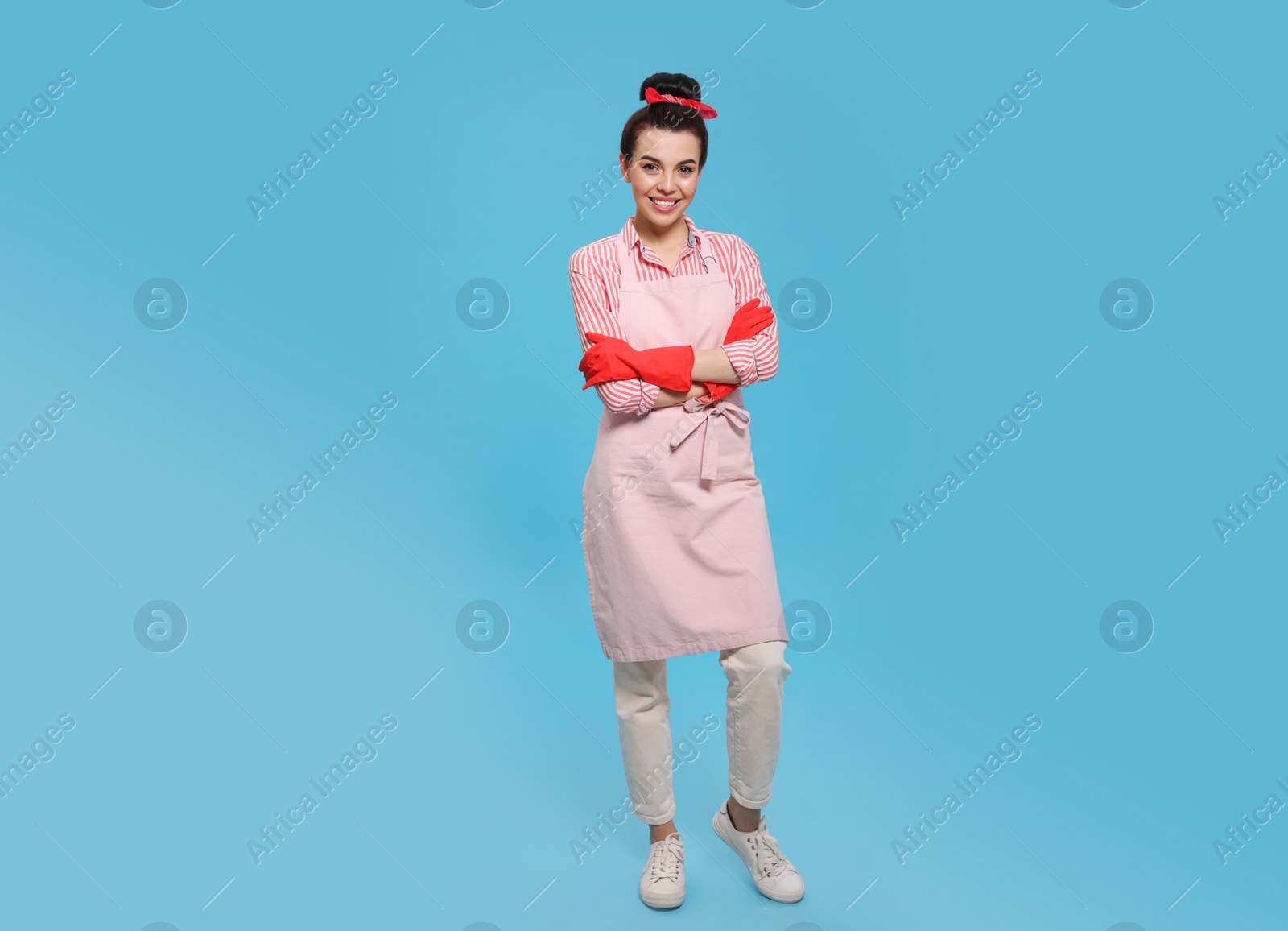 Photo of Housewife wearing rubber gloves on light blue background