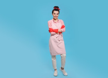 Photo of Housewife wearing rubber gloves on light blue background