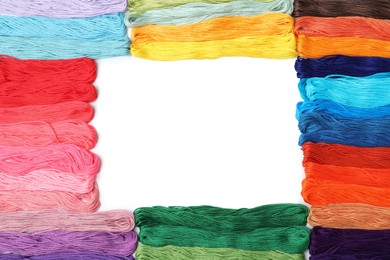 Frame of colorful embroidery threads on white background, top view