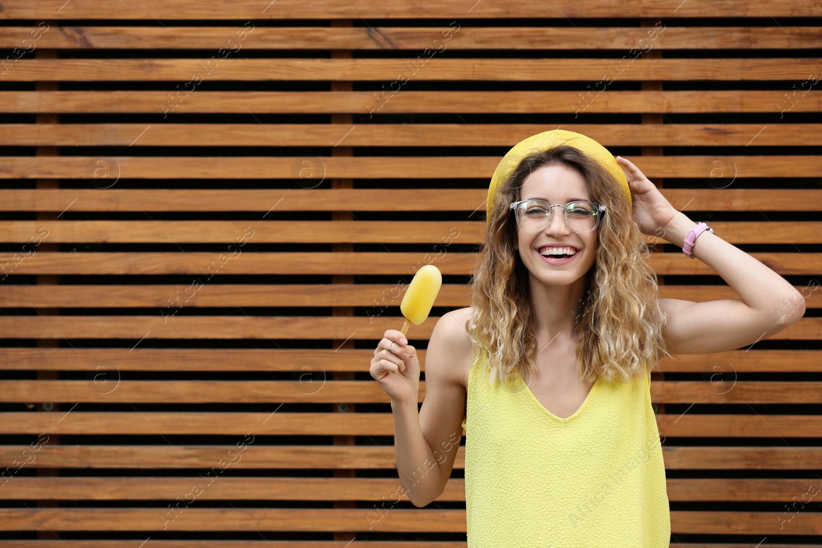 Photo of Happy young woman with delicious ice cream near wooden wall. Space for text