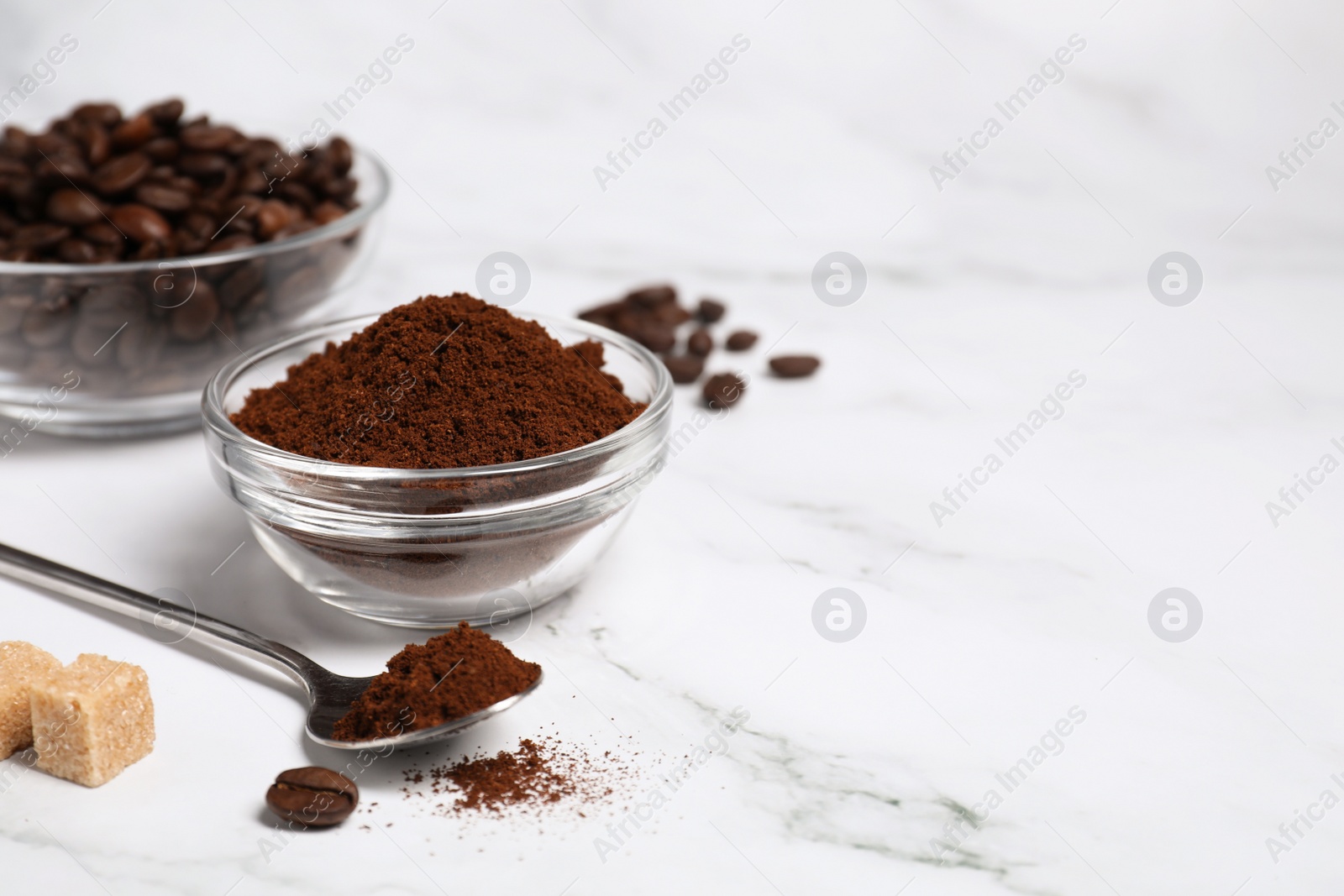 Photo of Glass bowl and spoon with instant coffee on white marble table. Space for text