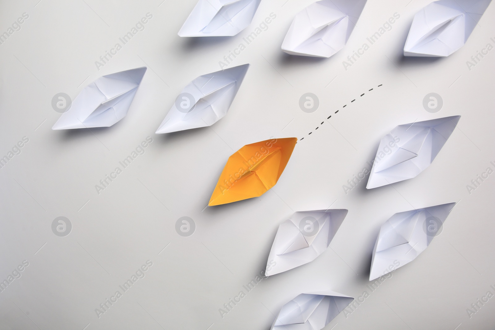 Photo of Yellow paper boat among others on white background, flat lay. Uniqueness concept