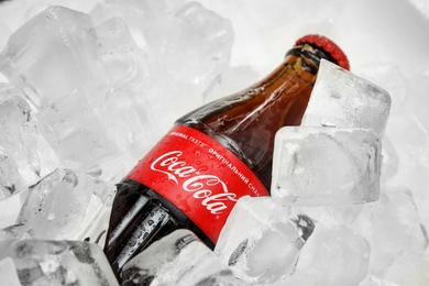 Photo of MYKOLAIV, UKRAINE - NOVEMBER 15, 2018: Bottle of Coca Cola on ice cubes, closeup