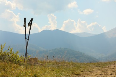 Photo of Trekking poles and hiking boots in mountains on sunny day. Space for text