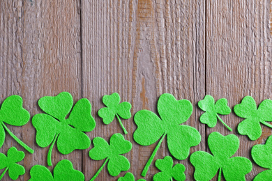 Photo of Flat lay composition with clover leaves on wooden table, space for text. St. Patrick's Day celebration