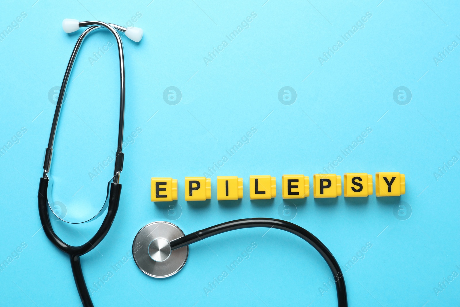 Photo of Word Epilepsy and stethoscope on light blue background, flat lay. Space for text