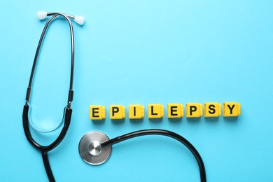 Photo of Word Epilepsy and stethoscope on light blue background, flat lay. Space for text