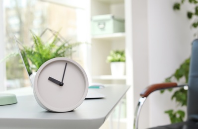 Photo of Analog alarm clock on table in office. Time to work