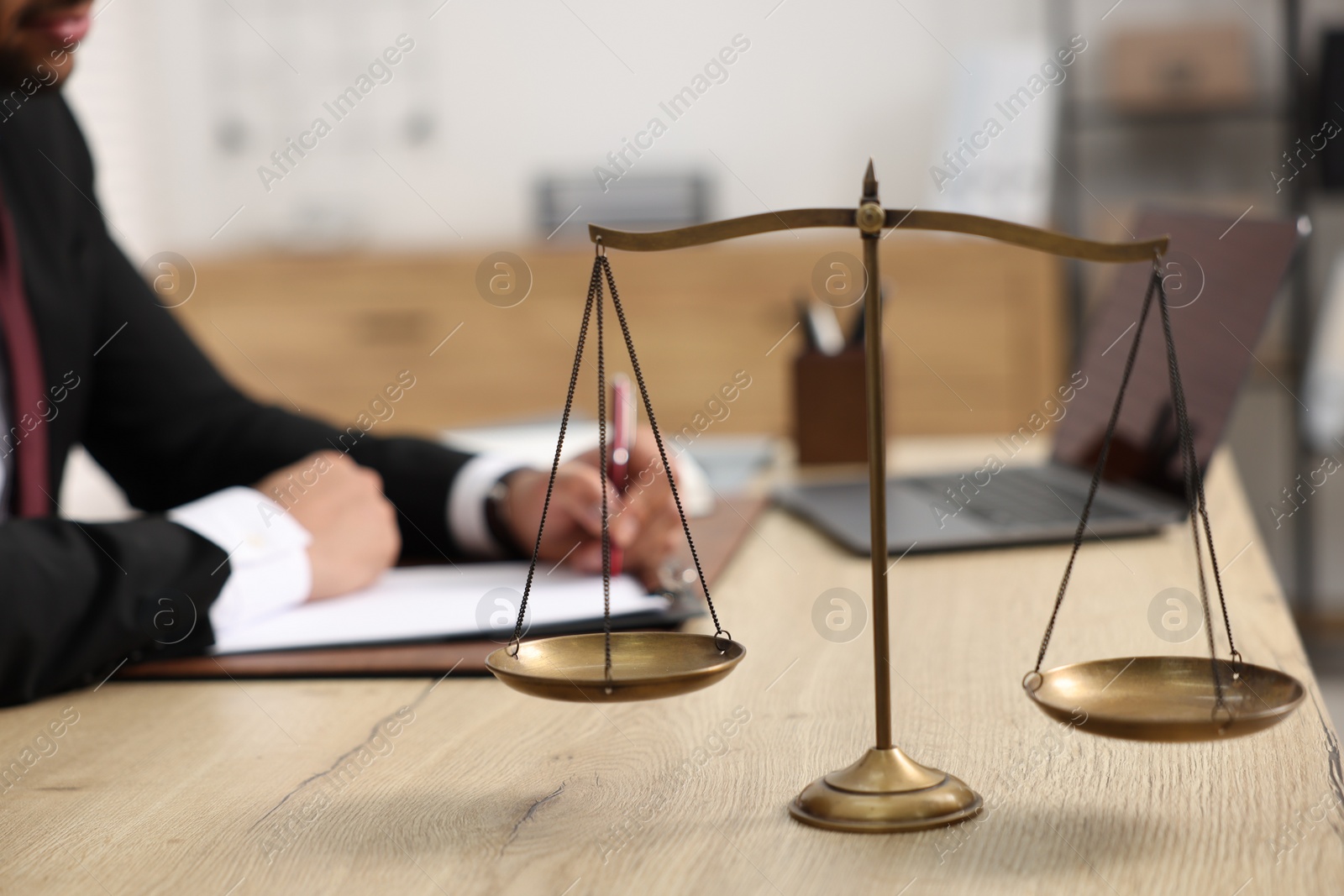 Photo of Lawyer working at table in office, focus on scales of justice