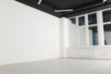 Photo of Blurred view of empty office room with black ceiling and windows. Interior design