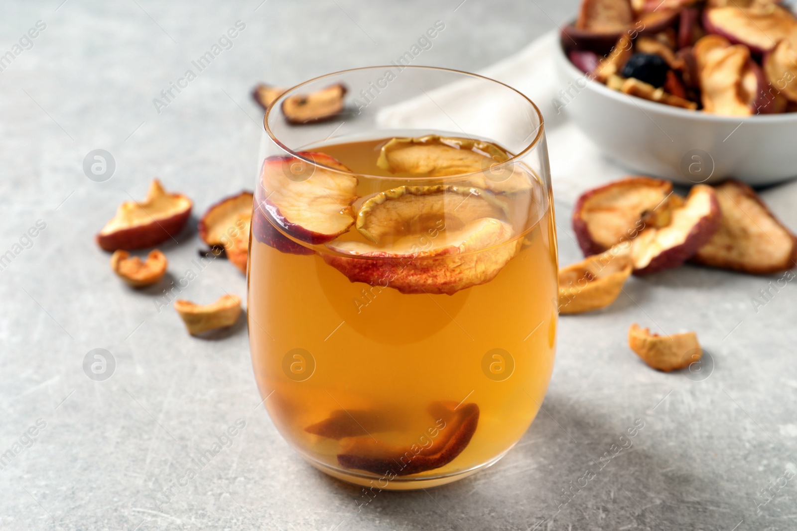 Photo of Delicious compote with dried apple slices in glass on grey table, closeup