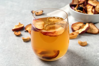 Delicious compote with dried apple slices in glass on grey table, closeup