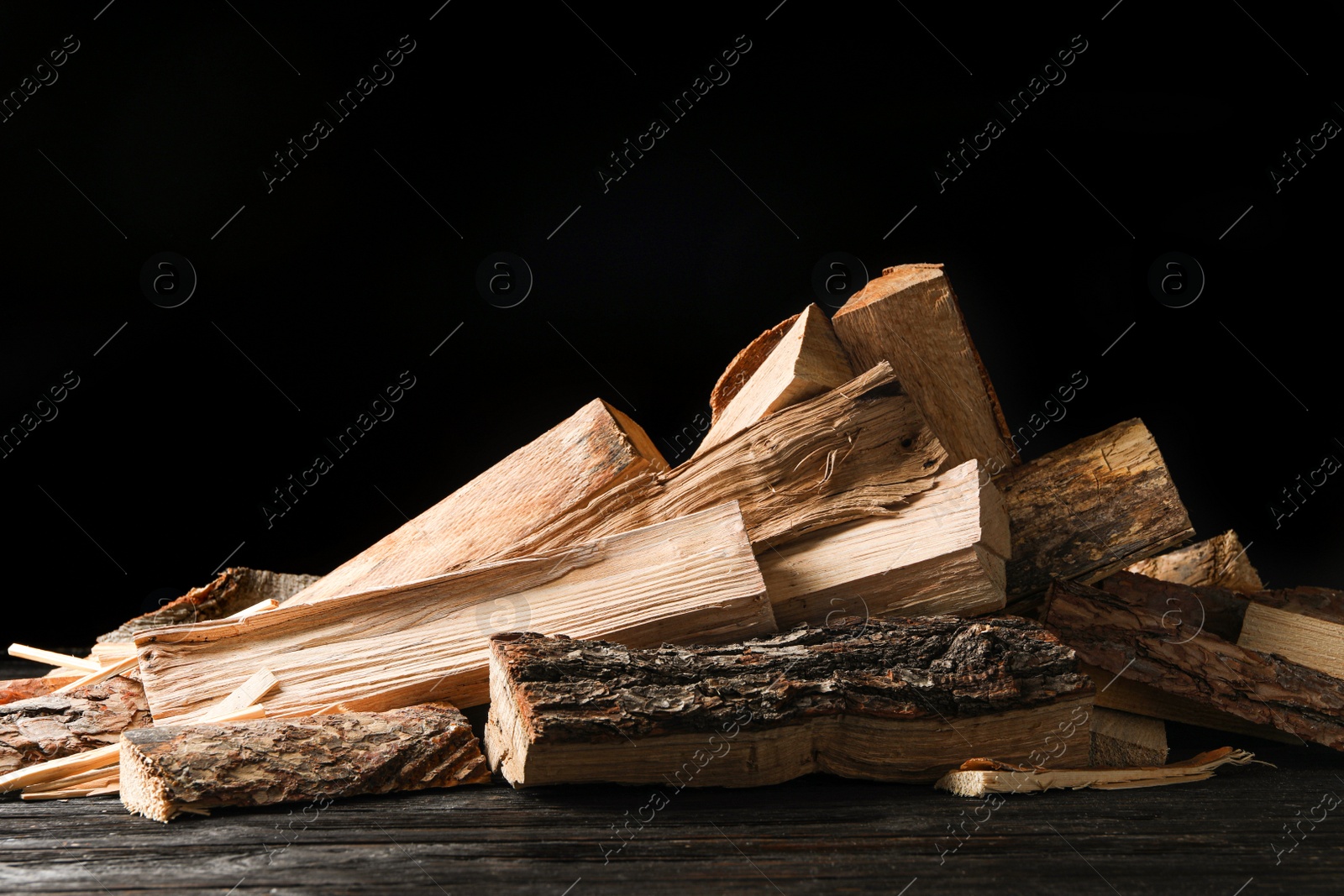 Photo of Cut firewood on table against black background