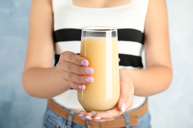 Photo of Woman holding tasty pear juice on light blue background, closeup