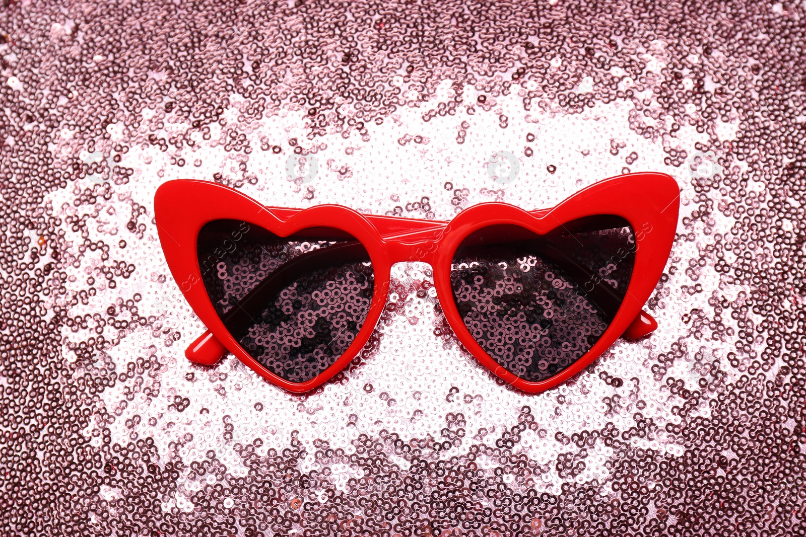 Photo of Red heart shaped sunglasses on bright background, top view