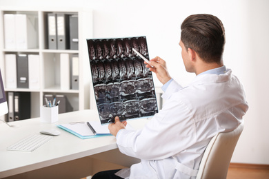 Orthopedist examining X-ray picture at desk in clinic