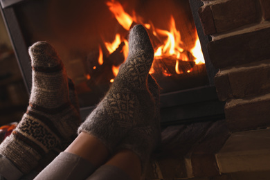 Couple resting near fireplace indoors, closeup. Winter vacation