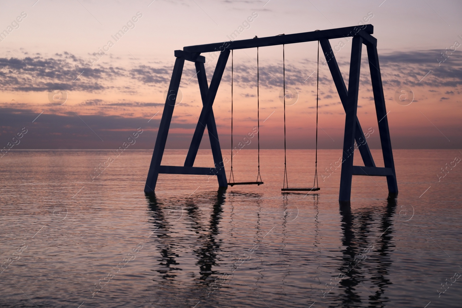 Photo of Picturesque view of swing in water on sunrise