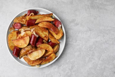 Photo of Delicious baked potato with thin dry smoked sausages and onion on gray table, top view. Space for text