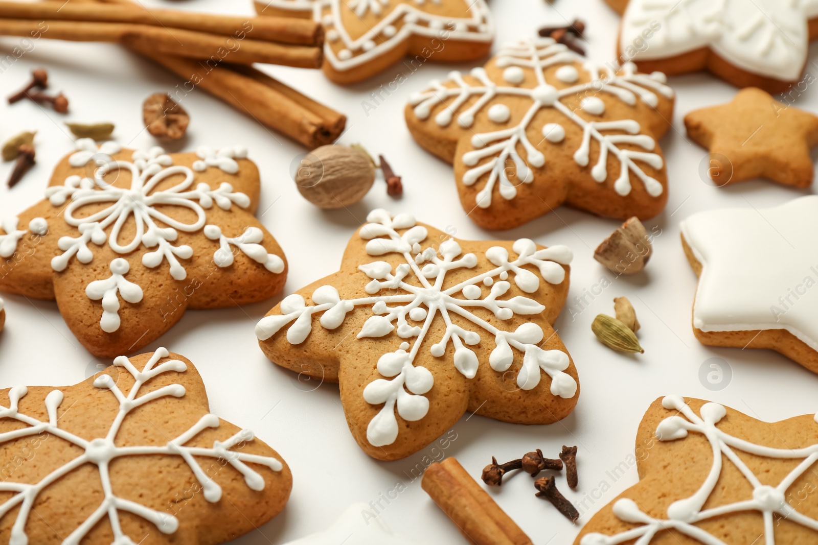 Photo of Tasty Christmas cookies with icing and spices on white background, closeup