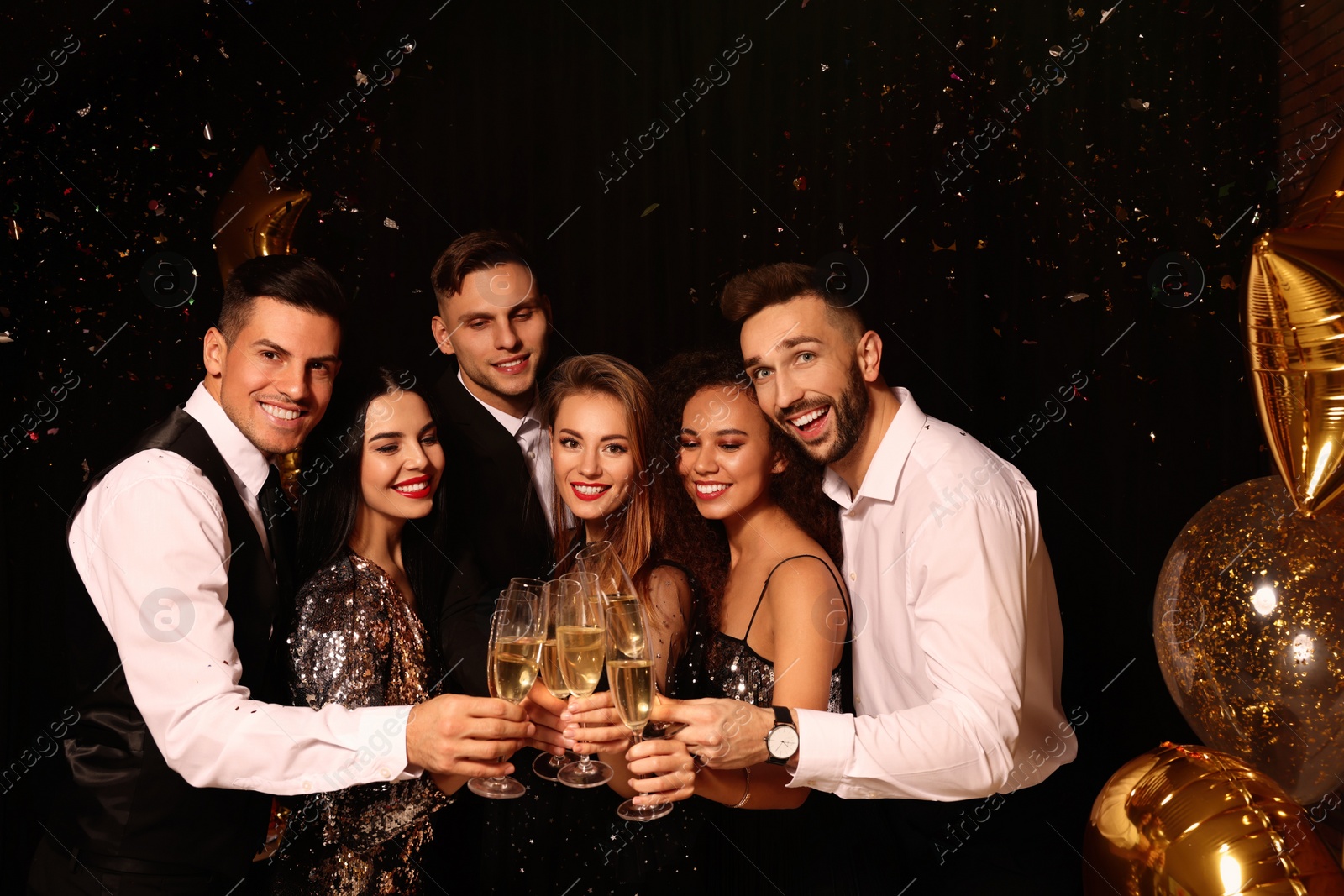 Photo of Happy friends with glasses of sparkling wine celebrating New Year on black background