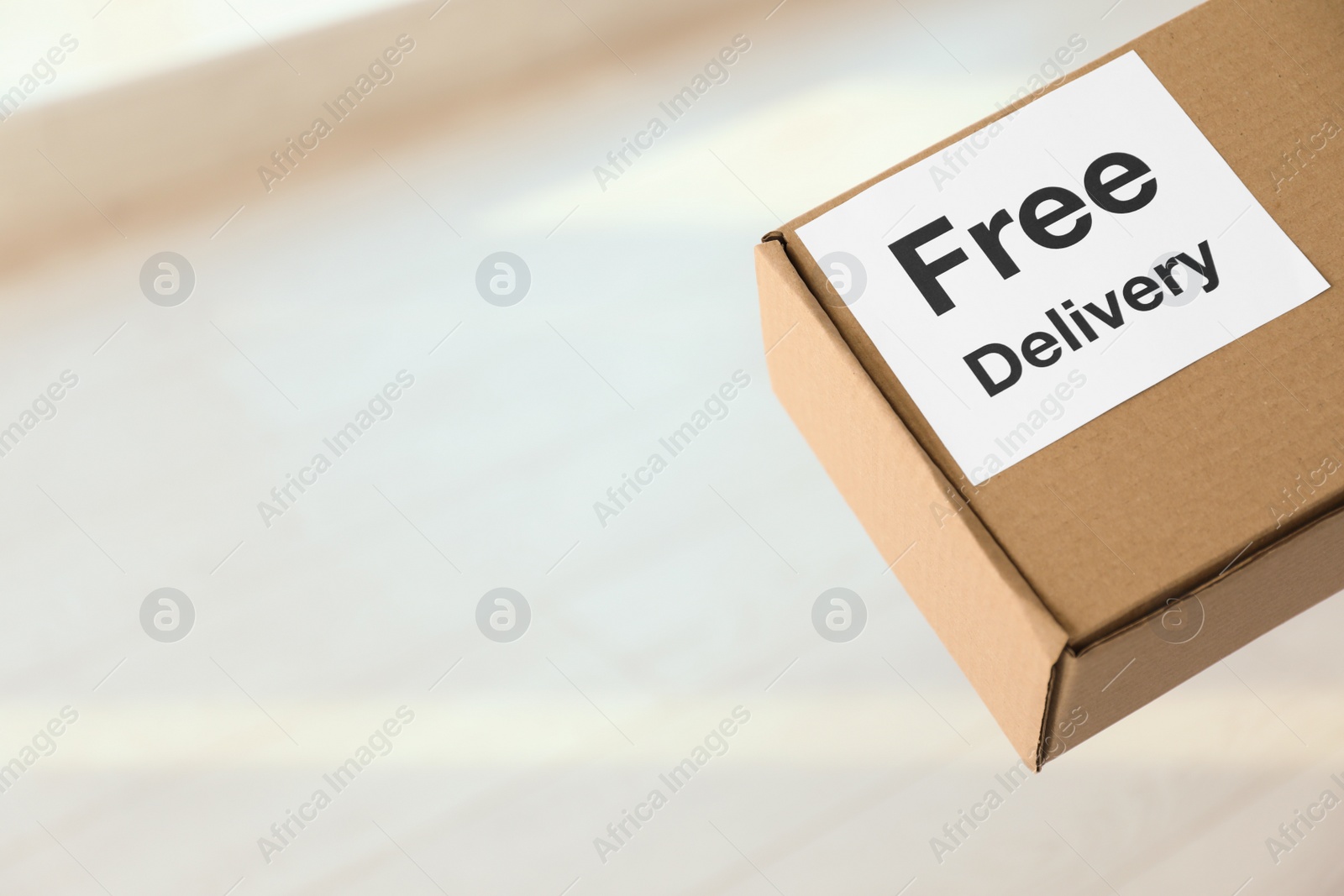 Photo of Parcel with sticker Free Delivery indoors, space for text. Courier service