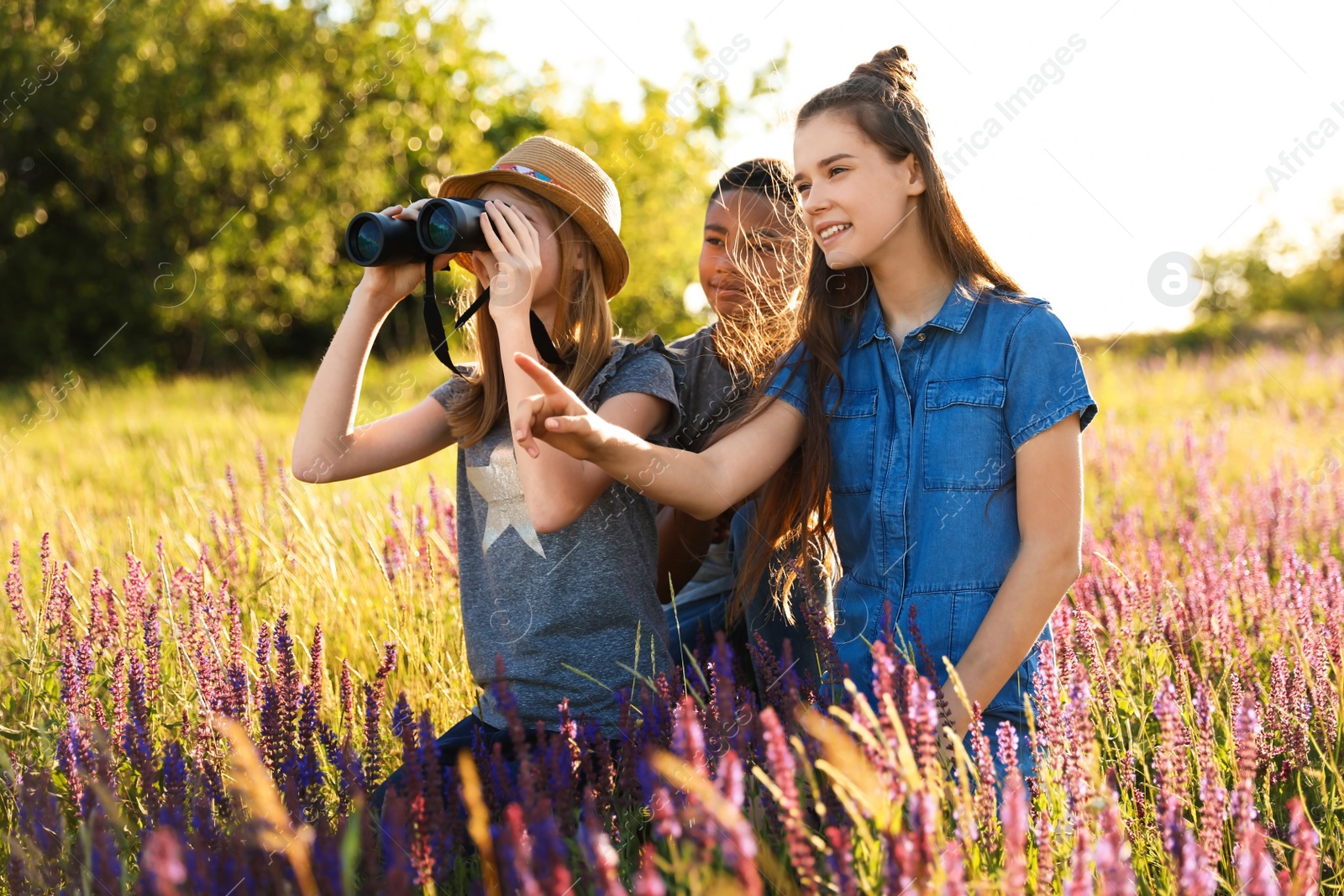 Photo of Group of children with binoculars in field. Summer camp