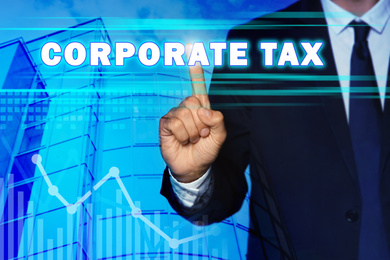 Image of Corporate tax concept. Double exposure of man touching virtual screen and modern building, closeup