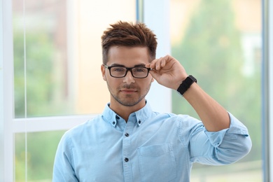 Photo of Portrait of handsome young man with glasses near window